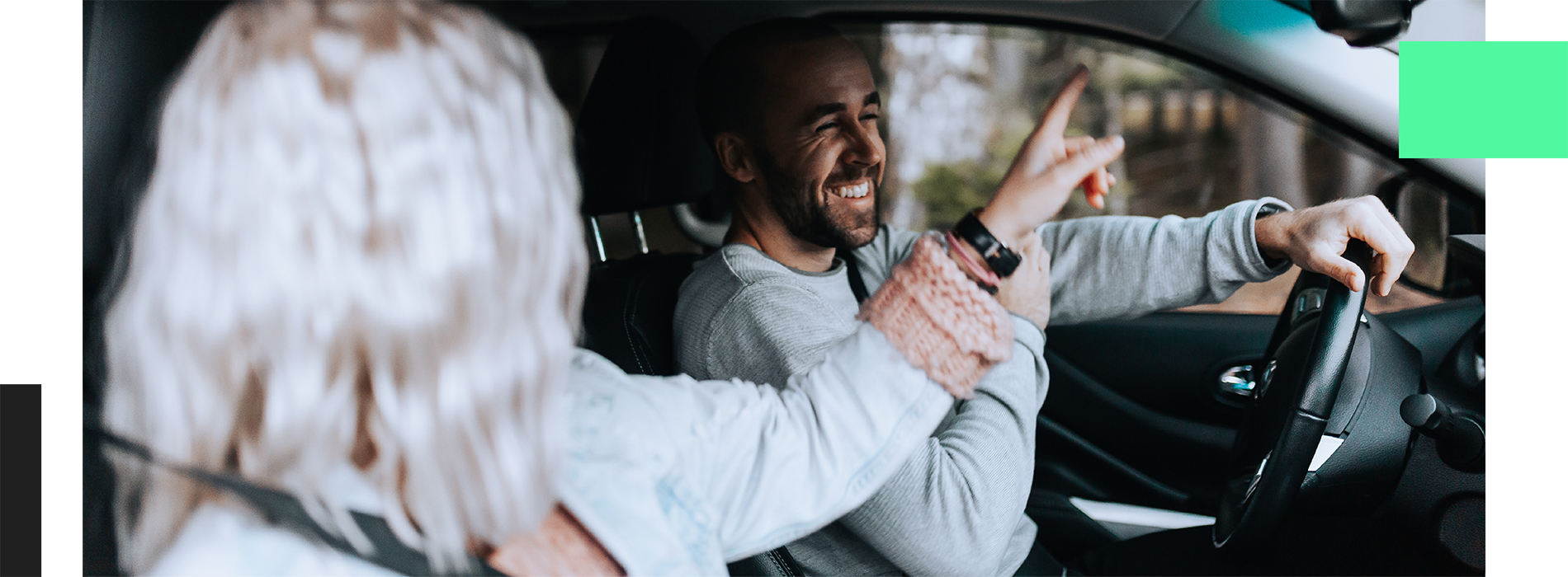 En man och en kvinna sitter i en bil och skrattar.